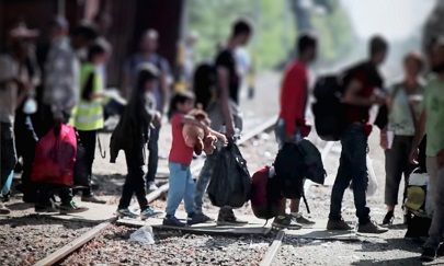 Photo of several refugees crossing train tracks on their way to the border